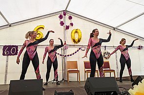 4 Frauen in Kostümen auf einer Bühne beim Tanzen auf dem 60-Jahre Sommerfest des Hufeland-hauses