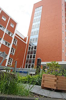 Das Hufeland-Haus mit seiner großen Fensterfassade oberhalb des Haupteinganges, davor ein gepflasterter Weg durch eine bepflanzte Anlage