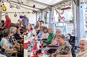 Seniorinnen und Senioren in einem Festzelt der 60-Jahres-Feier am Tisch
